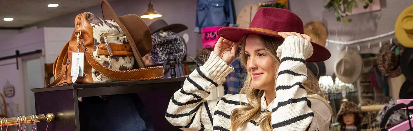 woman trying on a red cowboy hat in a boutique shop in yukon, ok