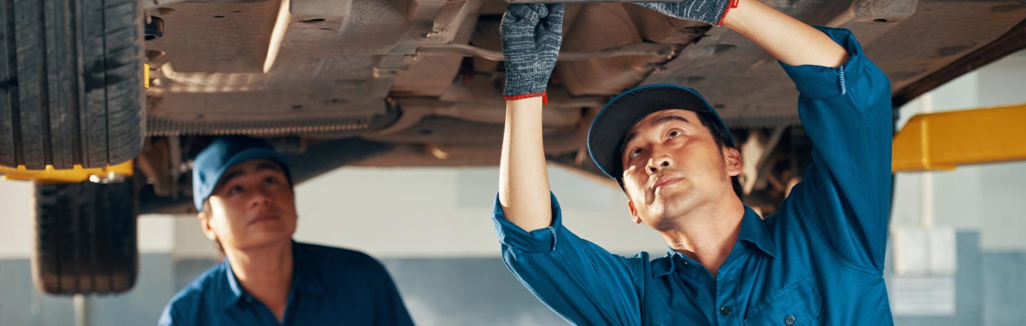 two mechanics working on a lifted vehicle