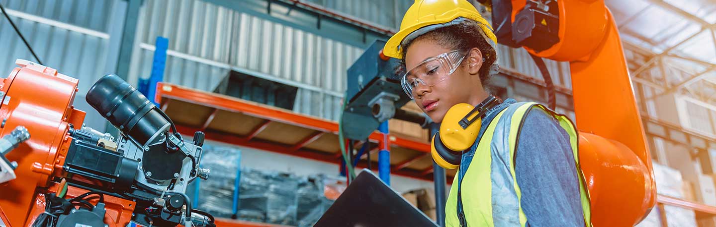 female engineer in hard hat programing robotic welding machine